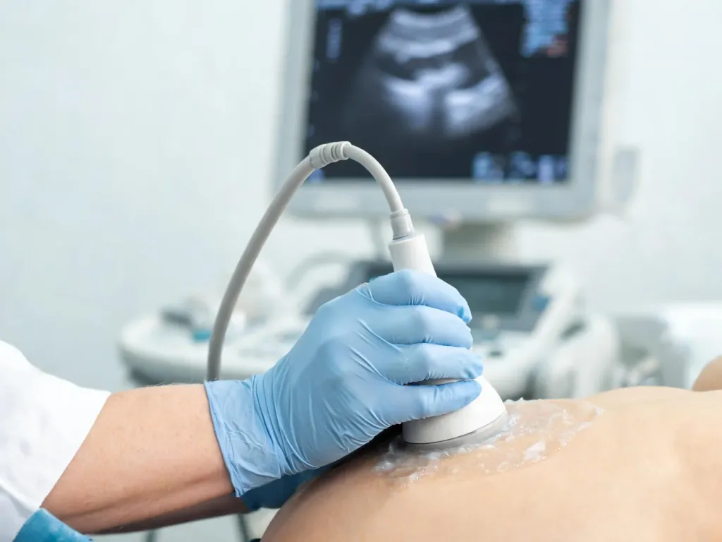 Lekarz wykonuje USG górnej części brzucha pacjenta, obrazowanie wątroby w spokojnej, jasnej sali klinicznej.